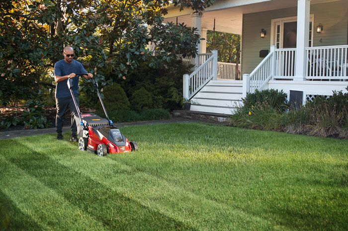 Man using lawnmower to create stripes in lawn