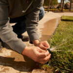 Close up of man's hands installing sprinkler in yard