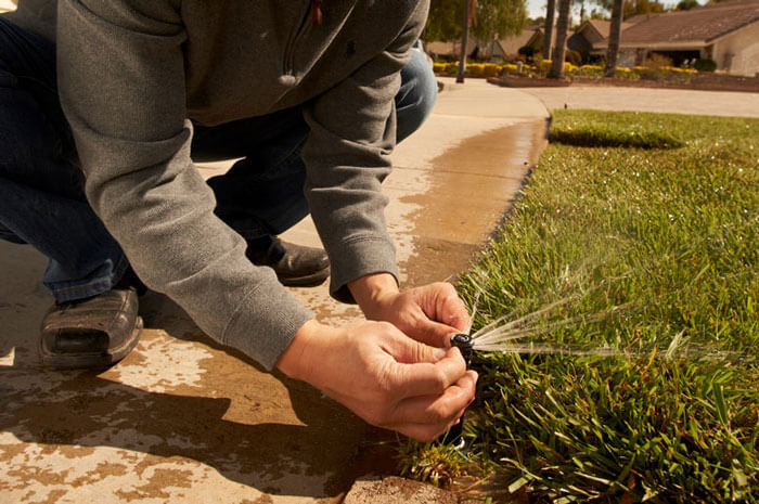 Close up of man's hands installing sprinkler in yard