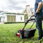 Man with one hand on his hip and the other on his Toro lawnmower in his front yard