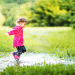 Little girl playing in a puddle of water