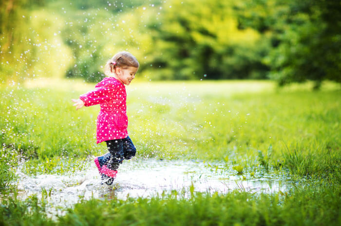 Little girl playing in a puddle of water