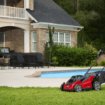 lawn mower sits in residential backyard in front of a pool
