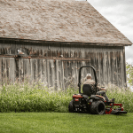 Man in a sit mower, mowing his backyard