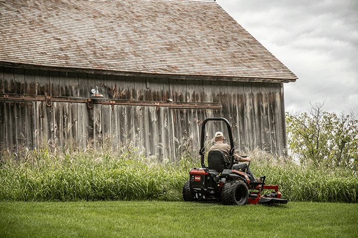 Man in a sit mower, mowing his backyard