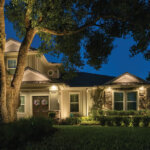 Front of suburban home at night illuminated by various outdoor lighting