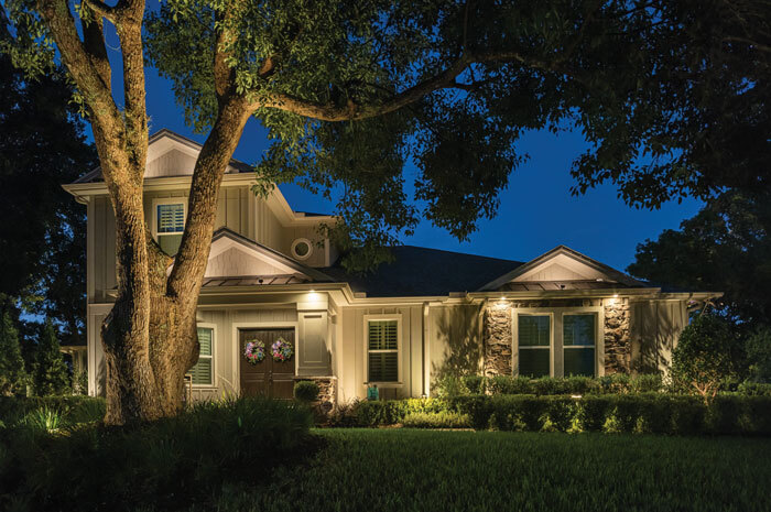 Front of suburban home at night illuminated by various outdoor lighting