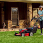 woman mowing front lawn with a walk mower