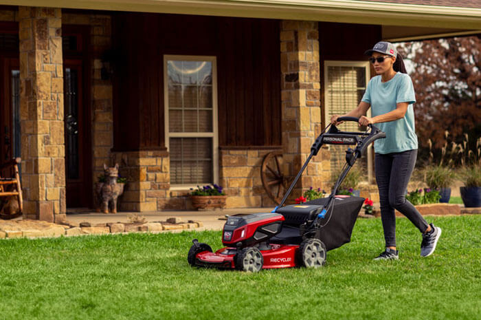 woman mowing front lawn with a walk mower