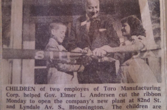 An old newspaper photo of two children cutting a ribbon to open a new Toro plant location with Gov. Elmer L Andersen assisting them