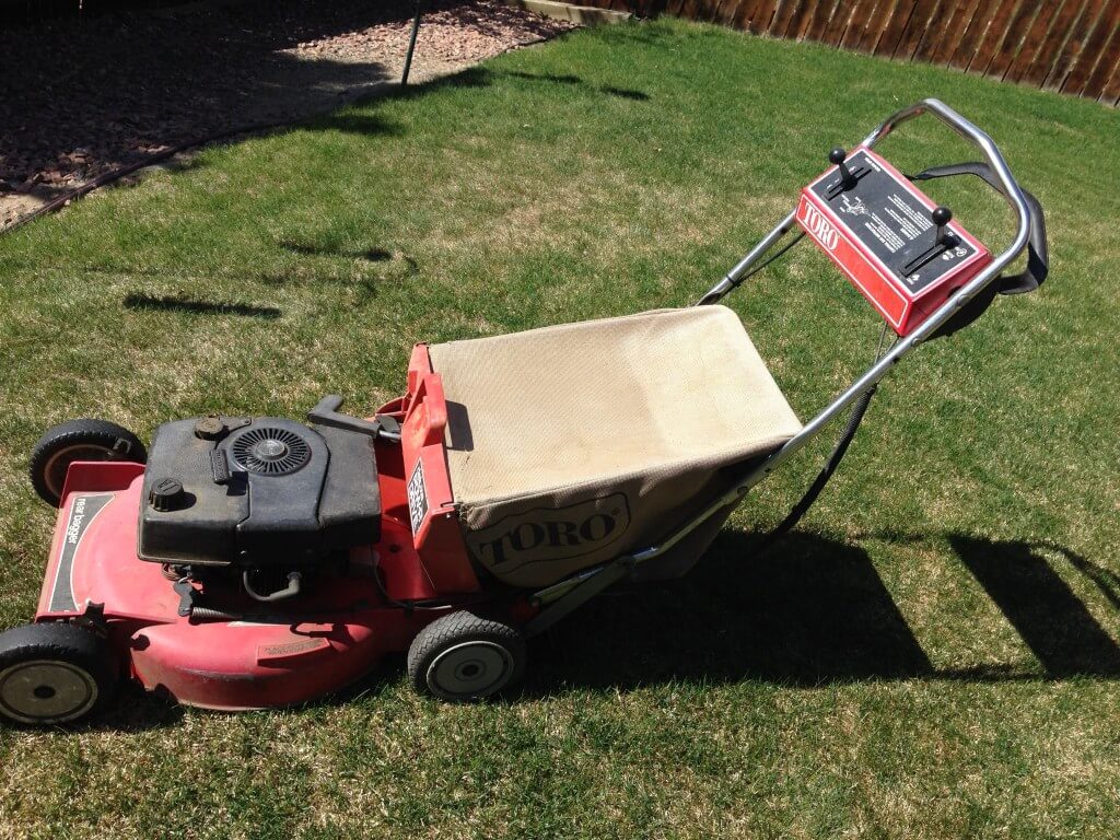 Toro lawnmower in a backyard with a brown fence in the background