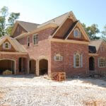 Brick house in the process of being built with nothing but broken concrete for a yard