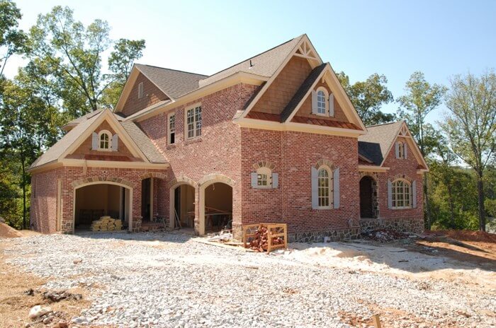 Brick house in the process of being built with nothing but broken concrete for a yard