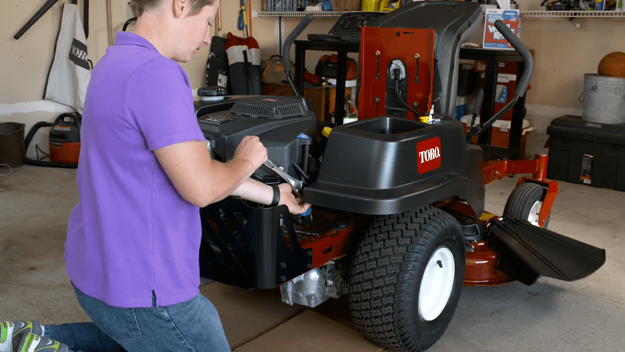 Person using wrench to conduct engine maintenance on Toro Zero Turn Mower