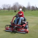 Man using large Toro riding mower on a golf course