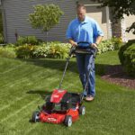 Man in blue shirt mowing front lawn