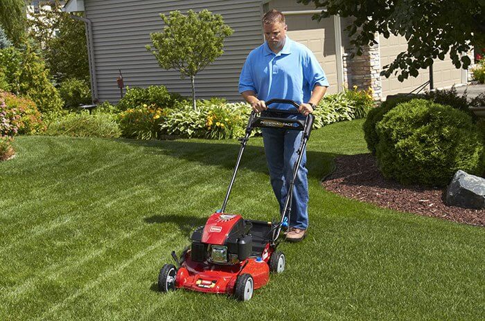 Man in blue shirt mowing front lawn