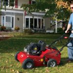 Man in blue shirt and glasses using Toro product to improve the health of his lawn