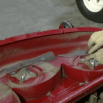 Close up of a man conducting lawnmower blade maintenance