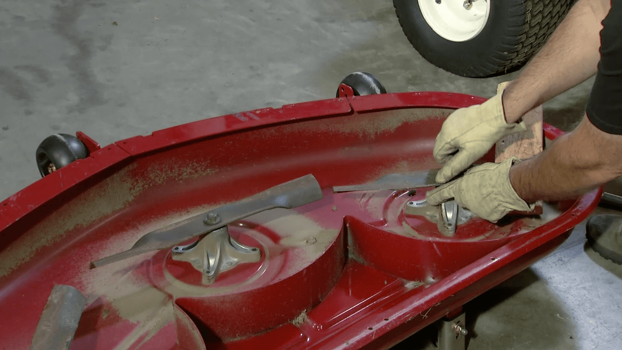 Close up of a man conducting lawnmower blade maintenance