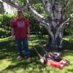 Man posing with a Toro lawnmower that is missing a wheel