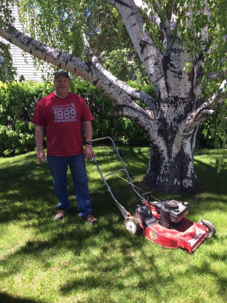 Man posing with a Toro lawnmower that is missing a wheel