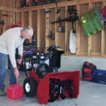 Man in garage fueling Toro product with tube