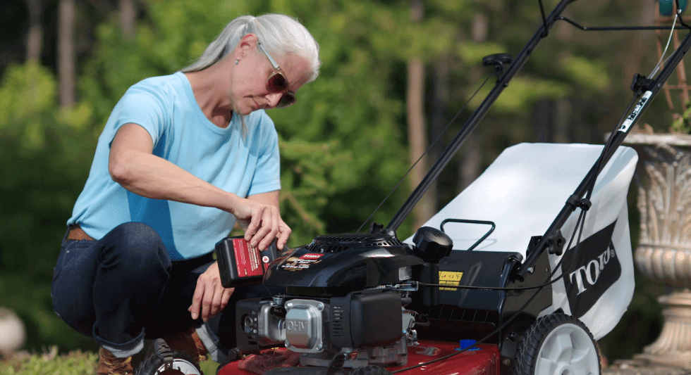 Woman pouring oil into Toro lawnmower