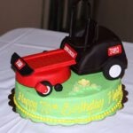 Green cake that says "Happy 70th Birthday" in frosting featuring a Toro lawnmower made of fondant on top