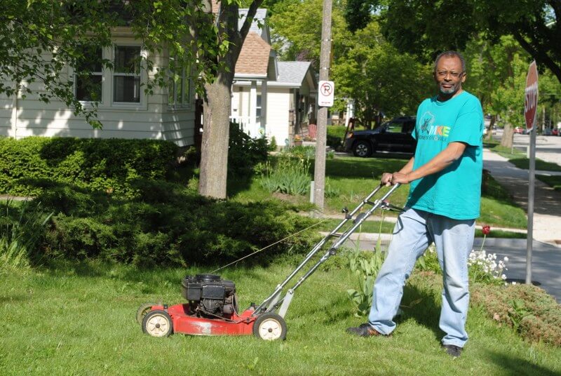 Man posing with Toro lawnmower as he mows his front lawn