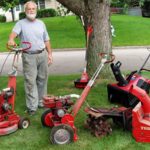 Man posing in green yard surrounded by four different models of Toro lawnmowers