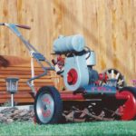 Image of older model of Toro lawnmower in a yard with a brown bench in the background