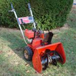 Toro 521 lawnmower in a yard with green bush behind it