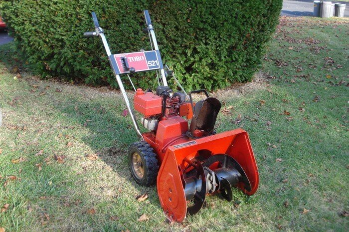 Toro 521 lawnmower in a yard with green bush behind it