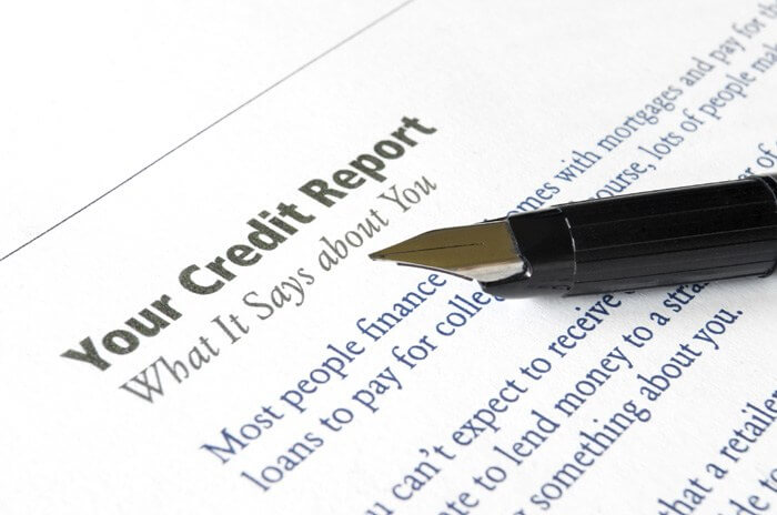 White paper that says "Your Credit Report" at the top and "What it says about you" under it with black ink pen resting on the page.