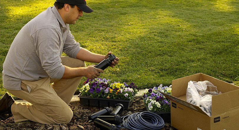 Man unboxing sprinkler system in garden