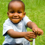 Small child smiling sitting in grass