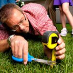 Man with scissors and a tape measurer to cut grass