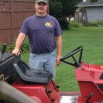 man standing on the side of his toro sit in lawn mower