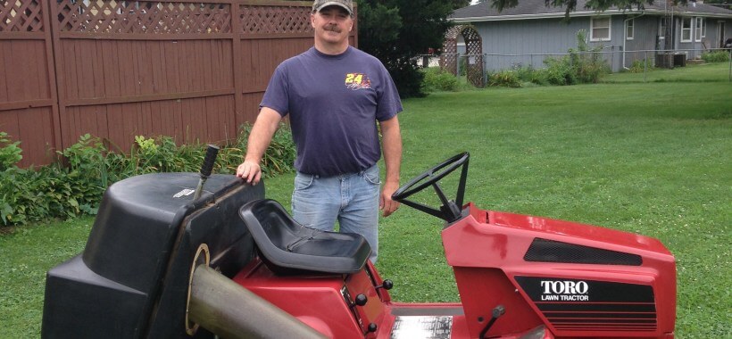 man standing on the side of his toro sit in lawn mower