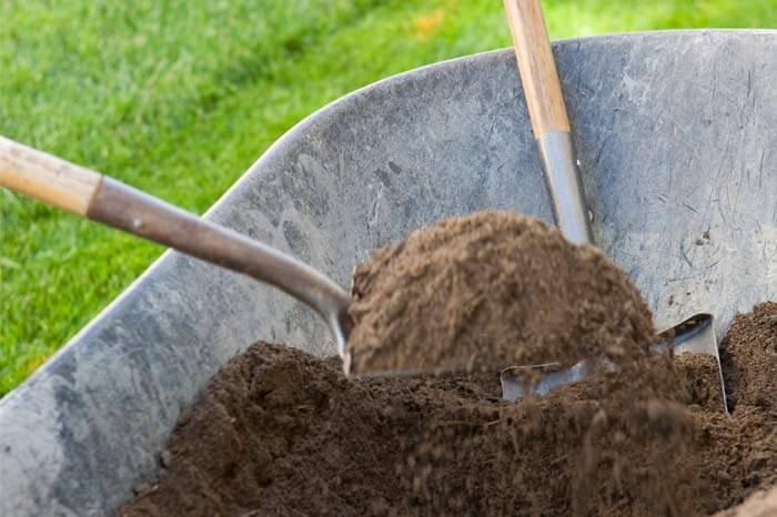 Shovels scooping dirt out of wheelbarrow