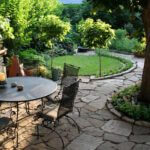 Rock path surrounded by green grass and trees featuring an outdoor patio table and chairs