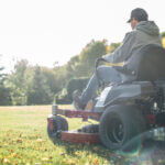 Rear view of a man sitting on a sit lawn mower