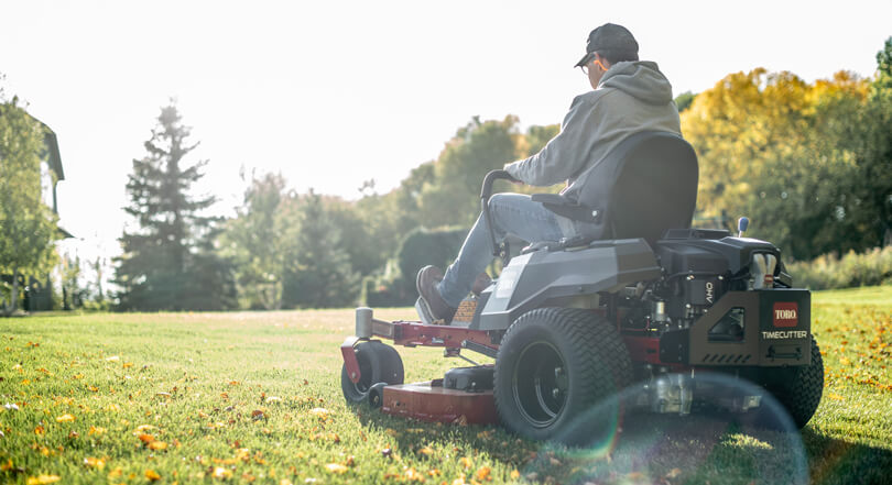 Rear view of a man sitting on a sit lawn mower