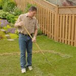Man removing thatch from yard with rake