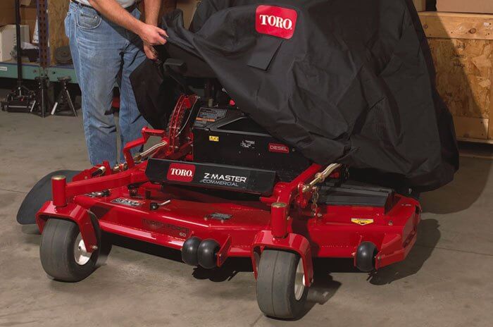 Man putting cover over lawnmower