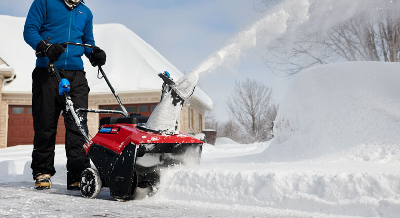 Man clearing driveway of snow with Toro snowblower