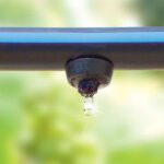 Close up of sprinkler with a single drop of water dripping from the spout