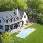 arial shot of sprawling backyard featuring firescaping features like a stone patio and pool