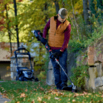 man trims along retaining wall with string trimmer